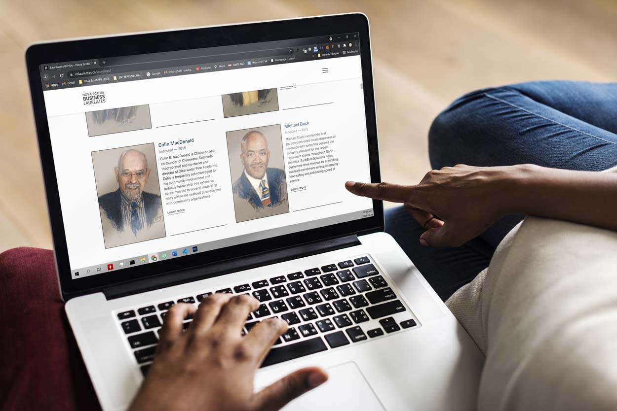 Photo of two people looking at a laptop with the laureate website on screen